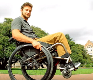 man in wheelchair with front wheels off the ground, demonstrating a wheelie